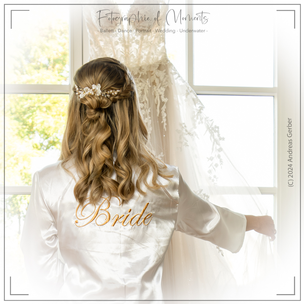 Braut schaut ihr Brautkleid vor dem Fenster an