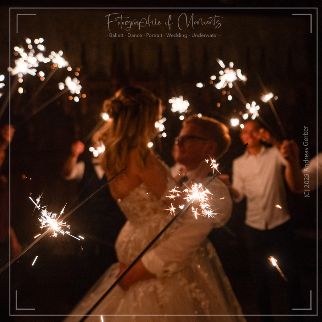 Braeutigam hebt Braut beim Tanzen hoch, umgeben von brennendem Sterneregen und Publikum.