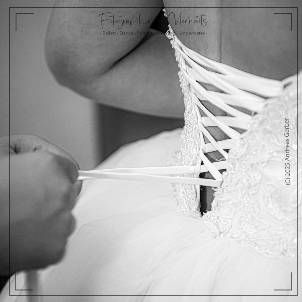 Braut bekommt das Korsage ihres Brautkleids zugezogen.