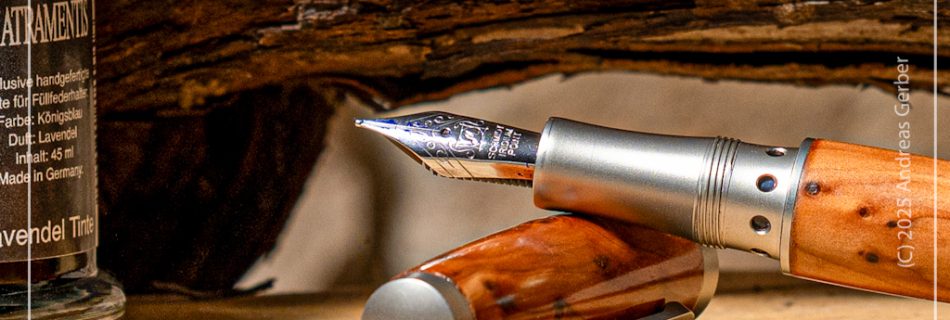 Edler Fueller aus Wachholderholz liegt neben klassischem Tintenfass.