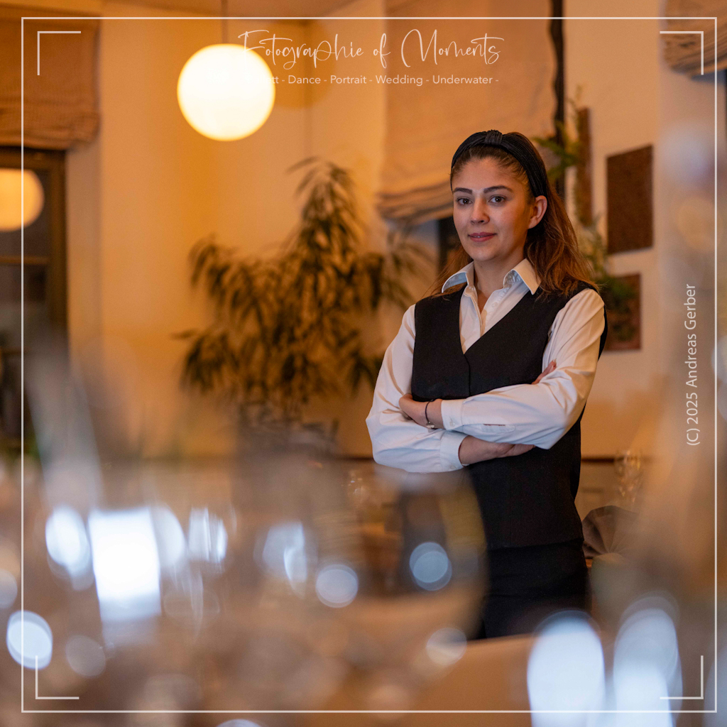 Restaurantmanagerin mit verschränkten Armen lächelt im Restaurant „Altes Schulhaus":